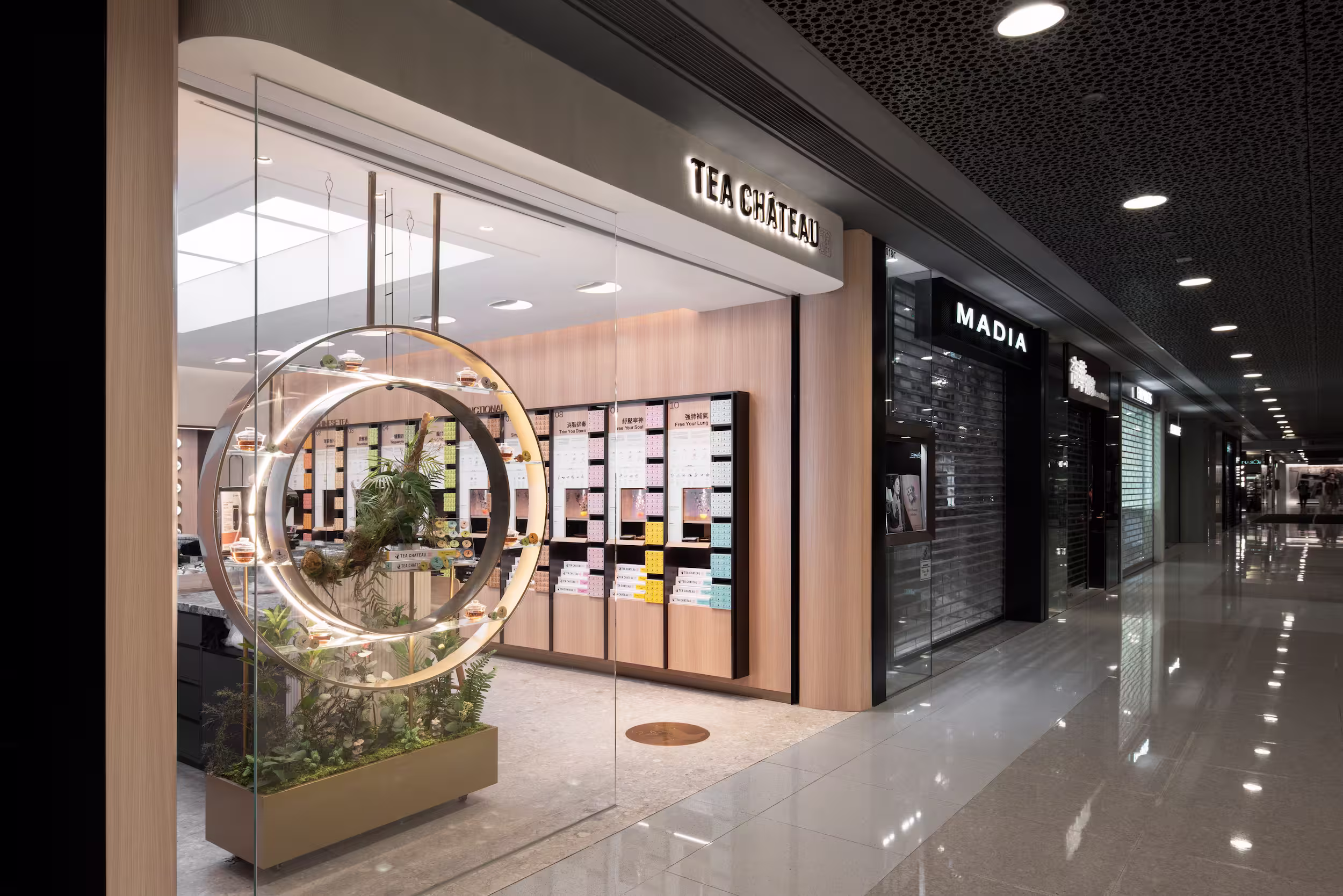 Tea Chateau oak bar stools detail at the marble-topped consultation counter with apothecary wall softly blurred beyond