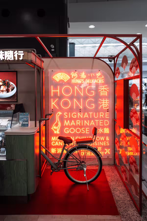Neon-lit sign for Hung's Delicacies featuring Hong Kong's signature marinated goose with a bicycle parked in front.