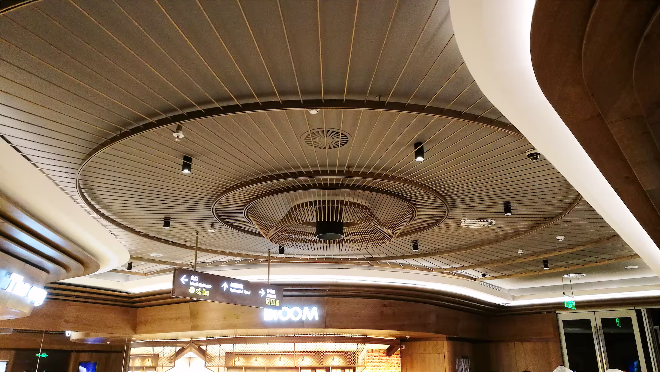 Completed layered rattan ceiling feature at K11 ATELIER Ningbo food hall with wayfinding signage and shopfronts.
