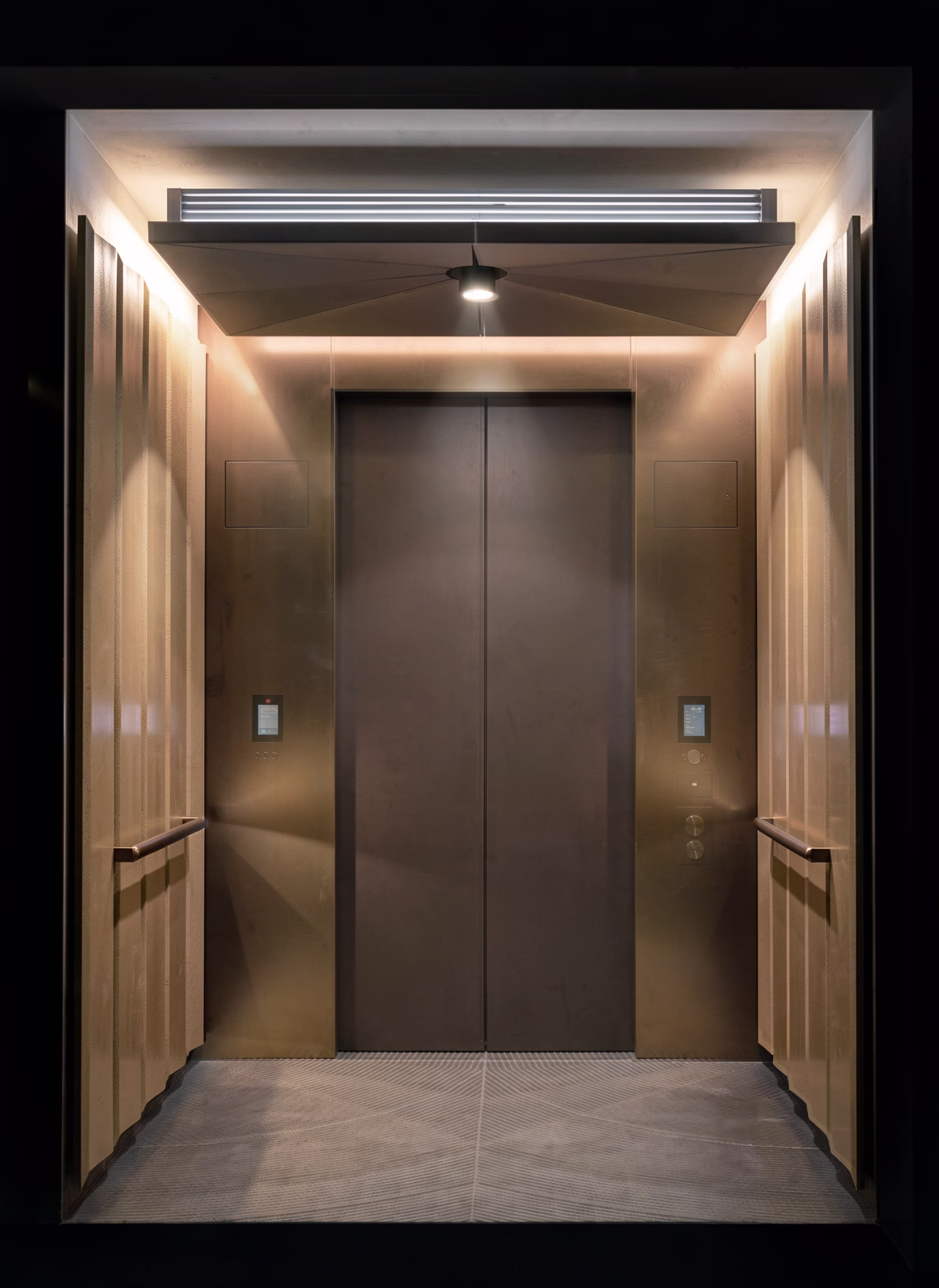 Lift lobby detail showing bronze doors, fluted panelling and the concealed lighting cove above