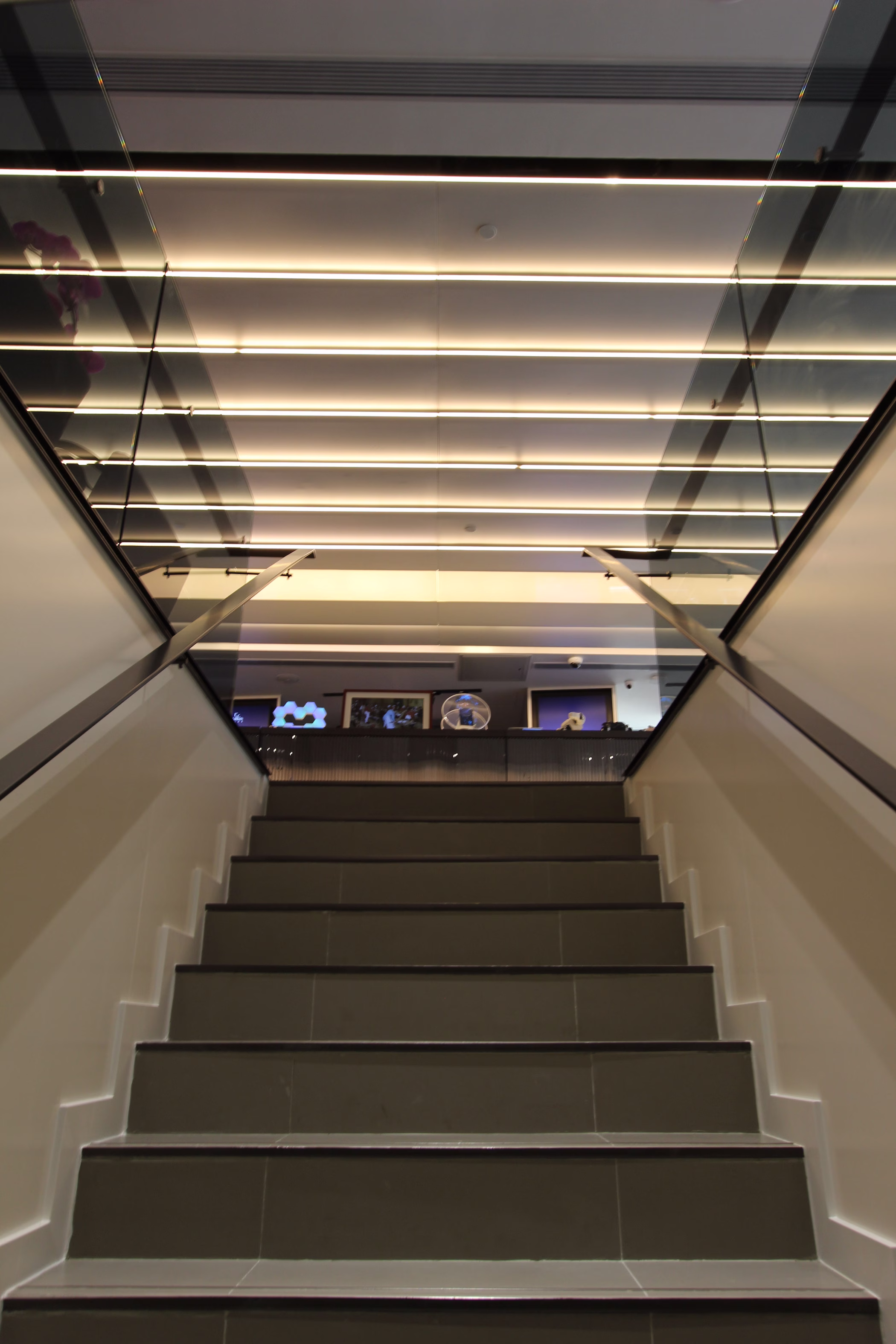 Staircase within the China Mobile flagship store lit by angled linear ceiling strips, leading down to the retail floor.