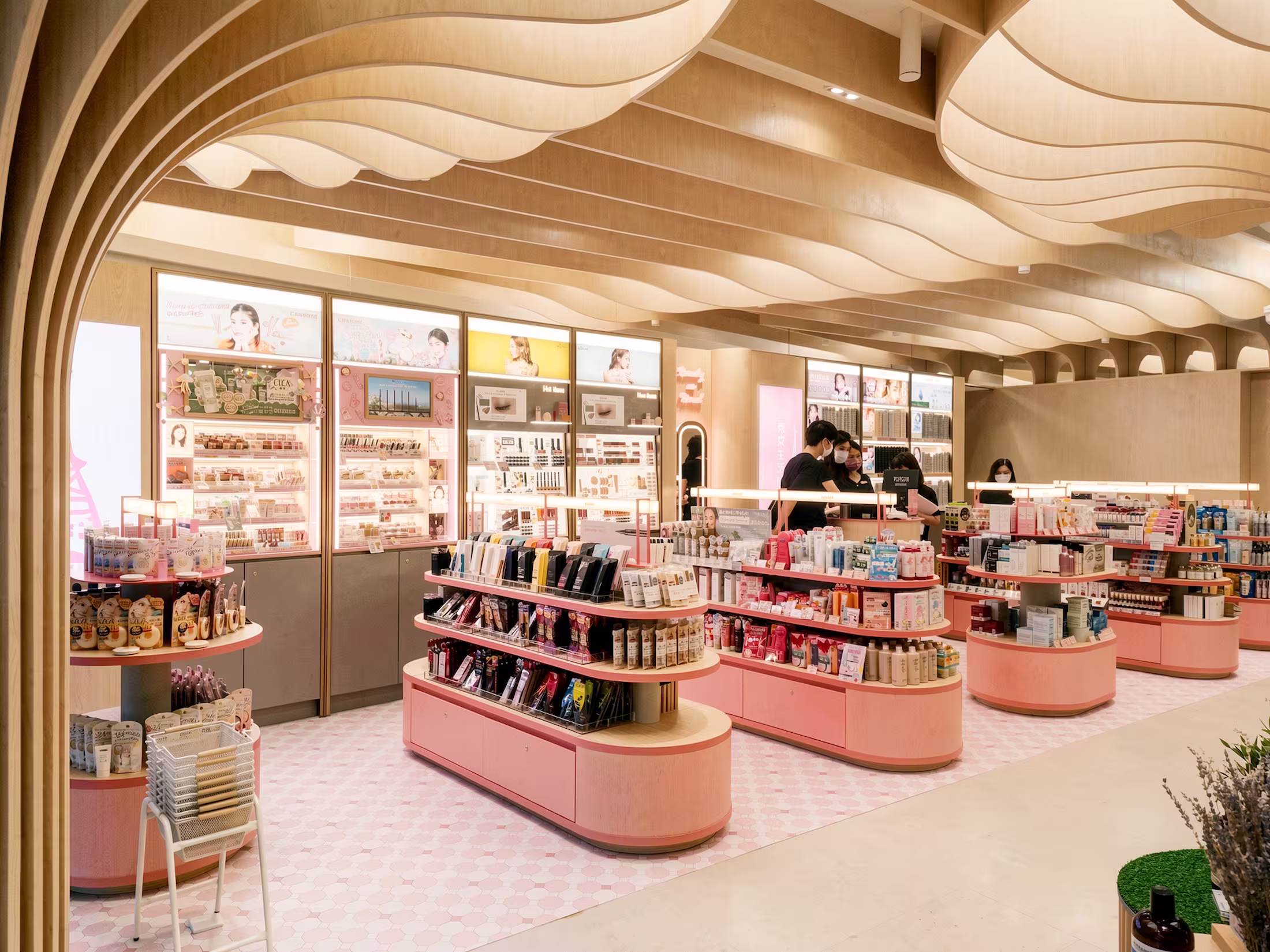 Department store beauty concession with a curved timber-slat ceiling, rounded display units, and soft pink accents.