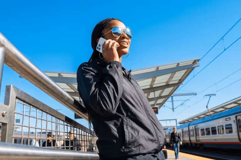 Young woman talking on a smartphone at a train station platform