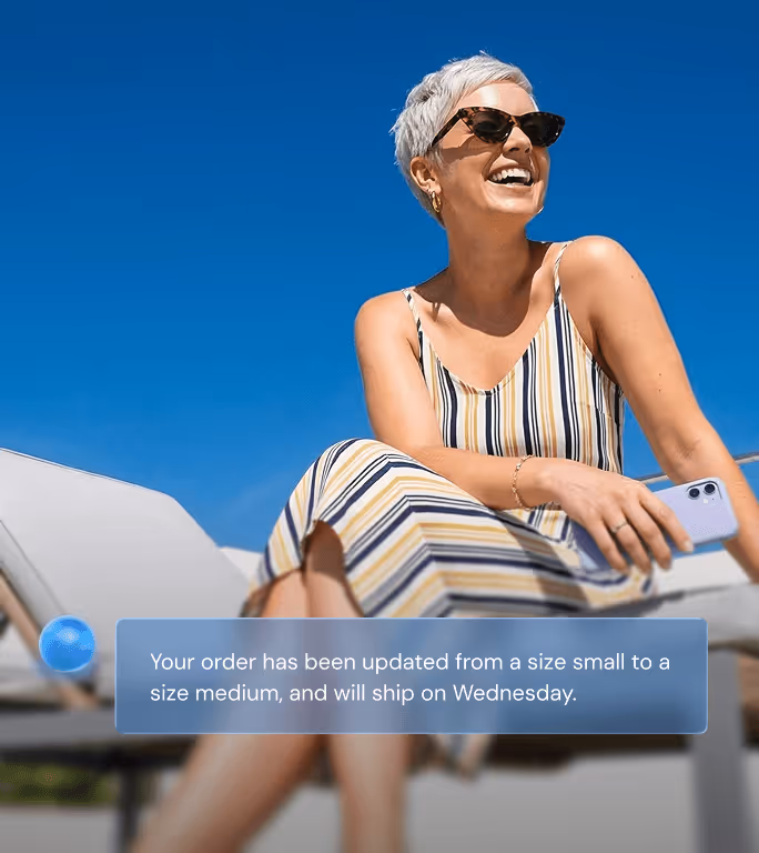 Smiling woman sitting outdoors on a lounge chair holding a smartphone