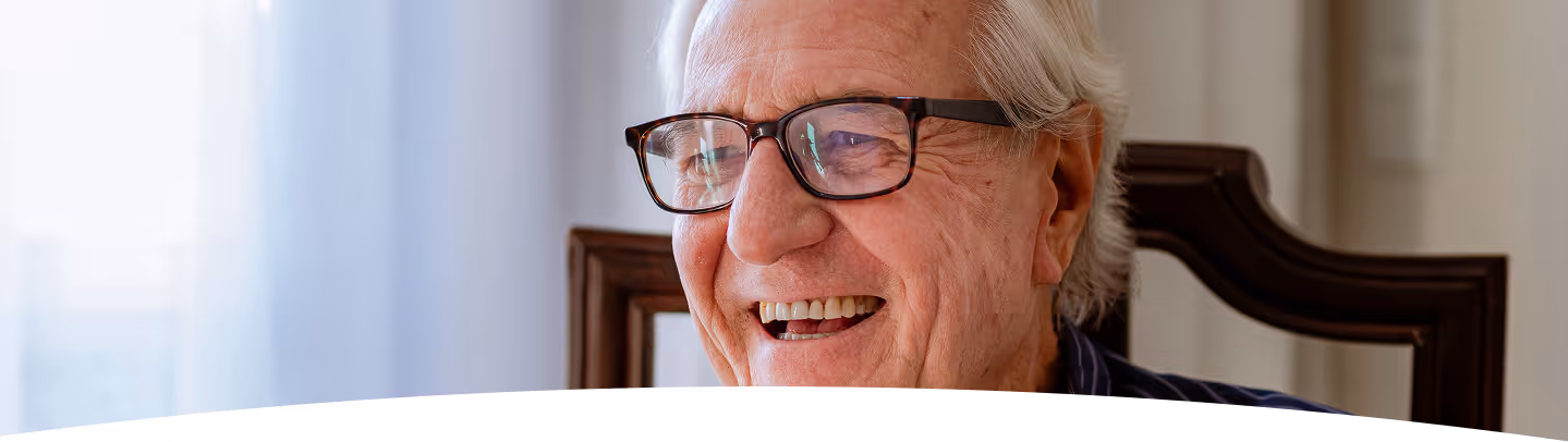 Un homme âgé souriant, aux cheveux gris et portant des lunettes