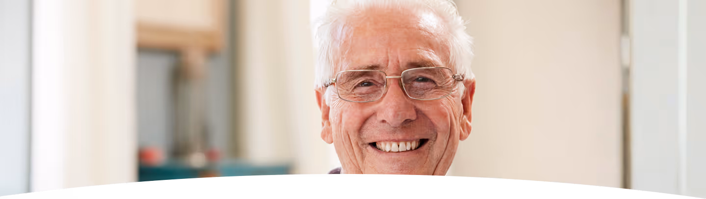 Vieil homme souriant, aux cheveux blancs et portant des lunettes