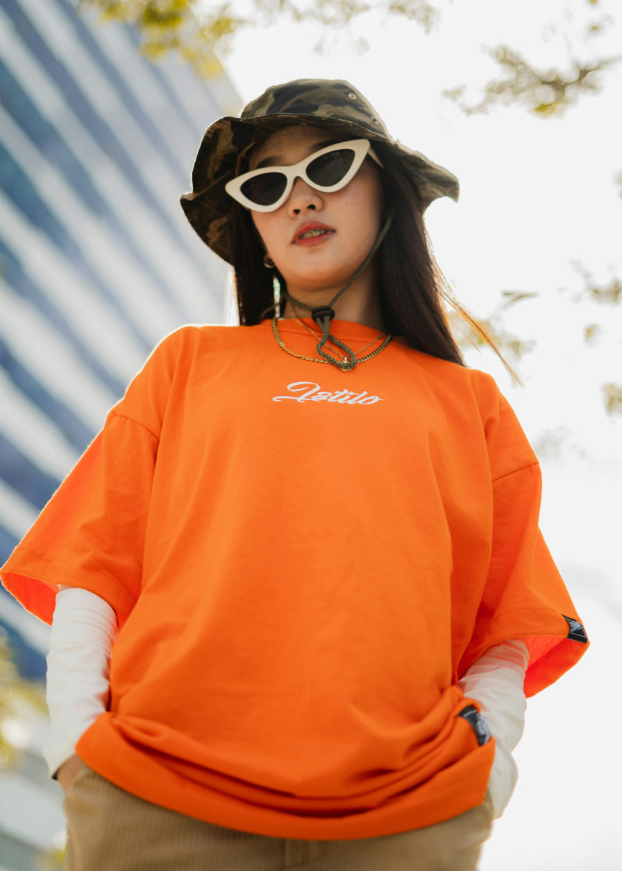 a girl dressed in an orange t-shirt with fashionable sunglasses on.