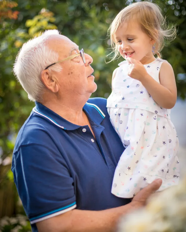 an older man holds his young grandchild