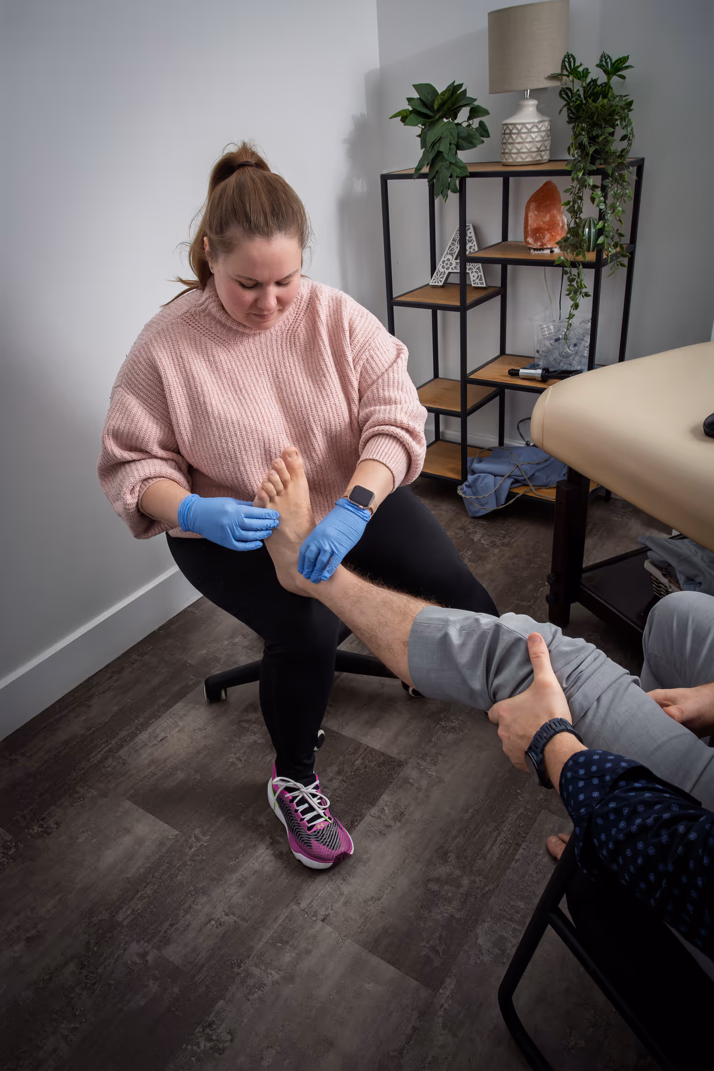 woman in pink sweater examines a patient's foot