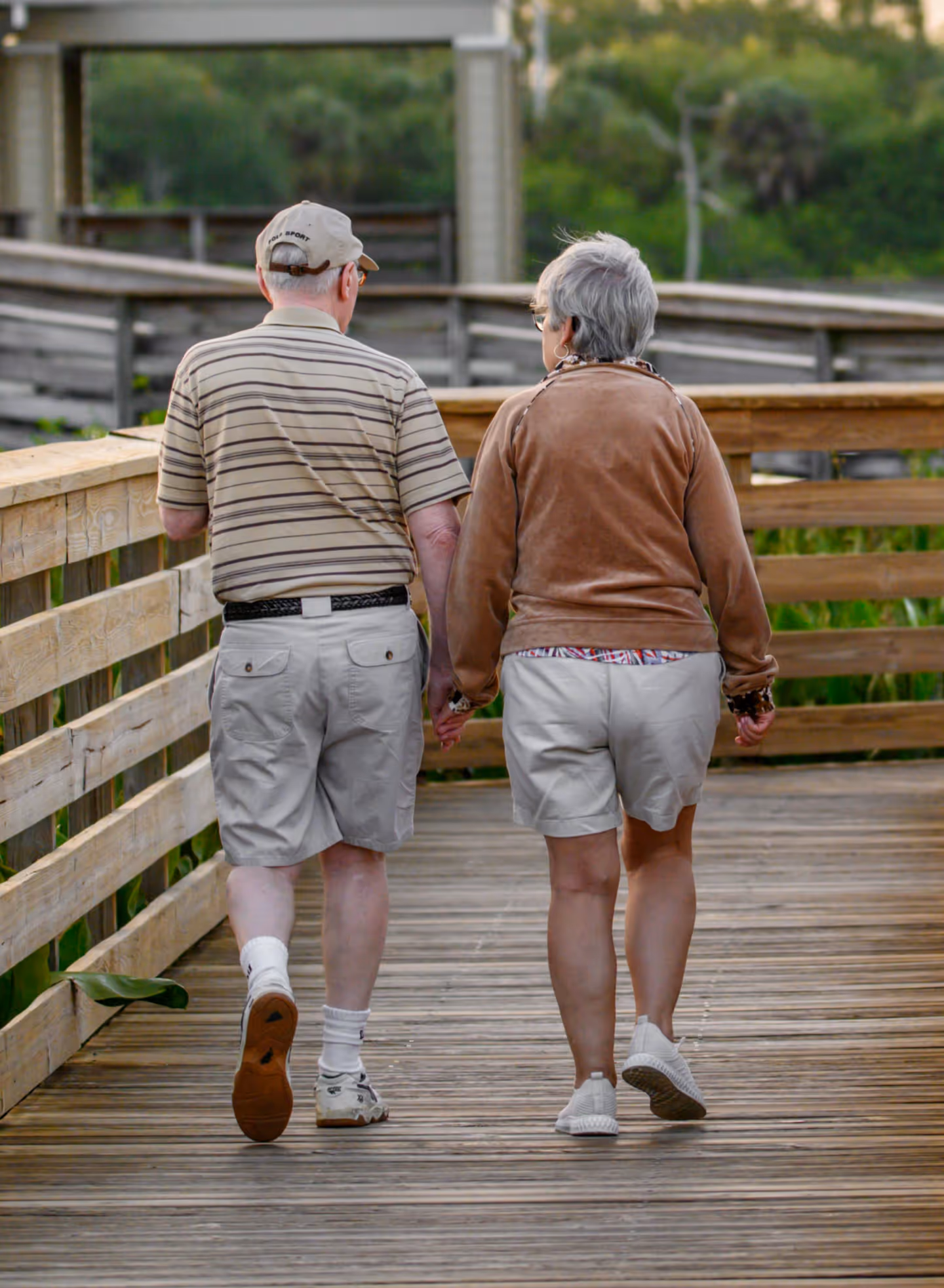 older couple walking comfortably on a boardwalk while on vacation
