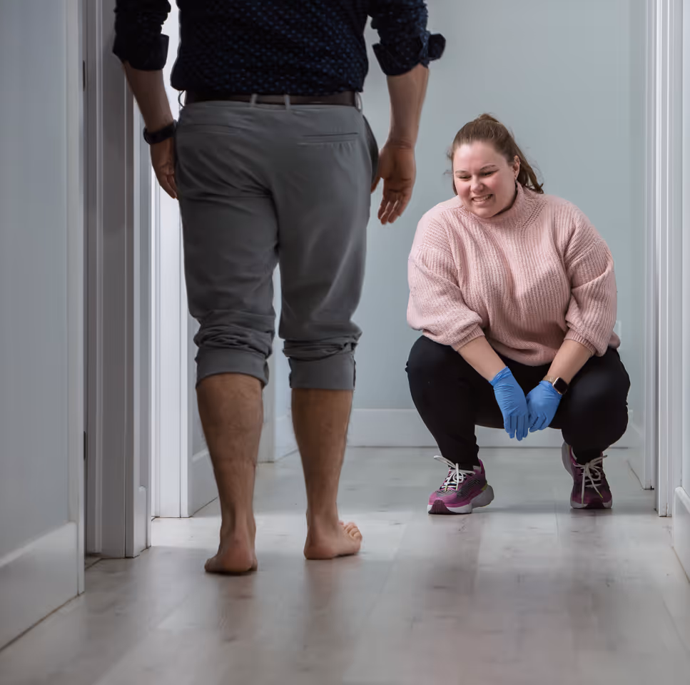 woman in pink sweater analyzes a patient's gait as he walks down a hallway