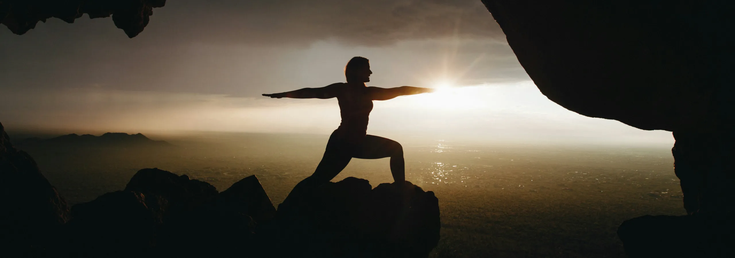 silhouette of a woman in a yoga pose with arms out