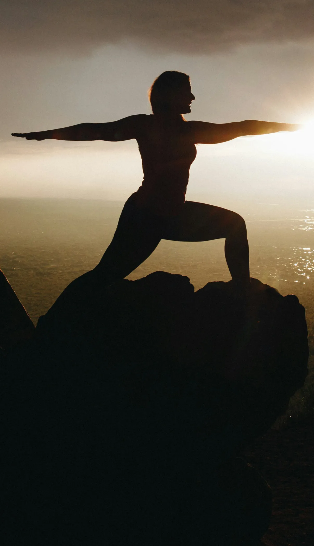 silhouette of a woman in a yoga pose with arms out