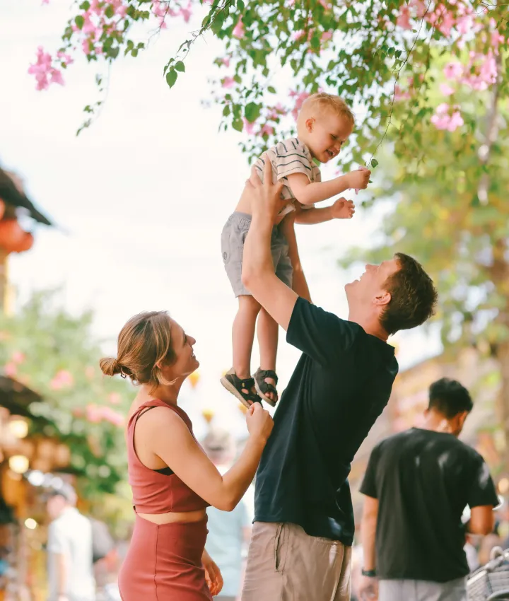 Father lifting a child as mother looks on.