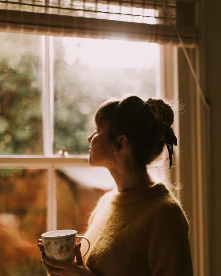 Young woman gazing out a window, contemplating her life.