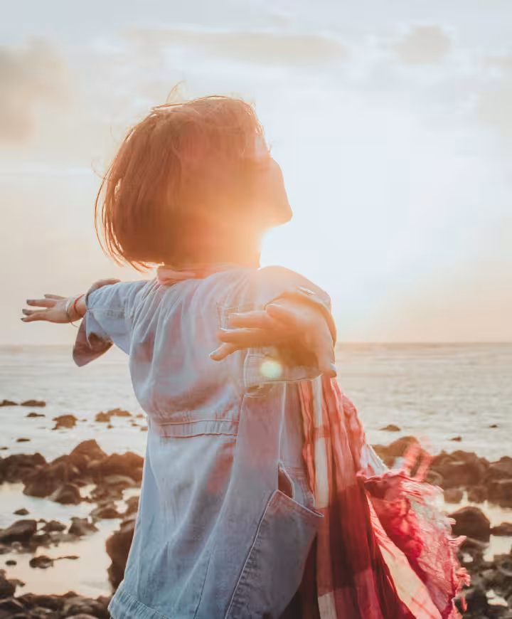 Happy confident woman with arms outstretched, greeting a sunny day.