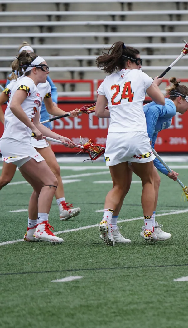 womens' sports teams playing lacrosse on a sports field