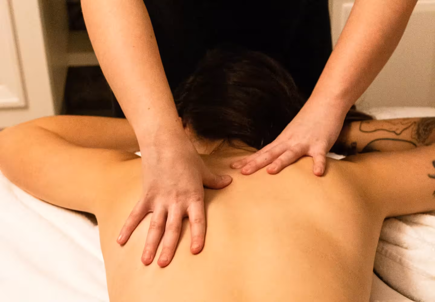 hands of massage therapist working on a patient's shoulders