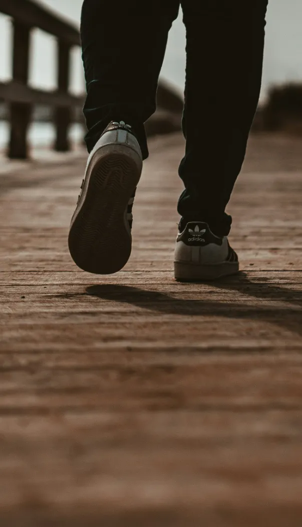 close-up of feet walking on a wooden boardwalk