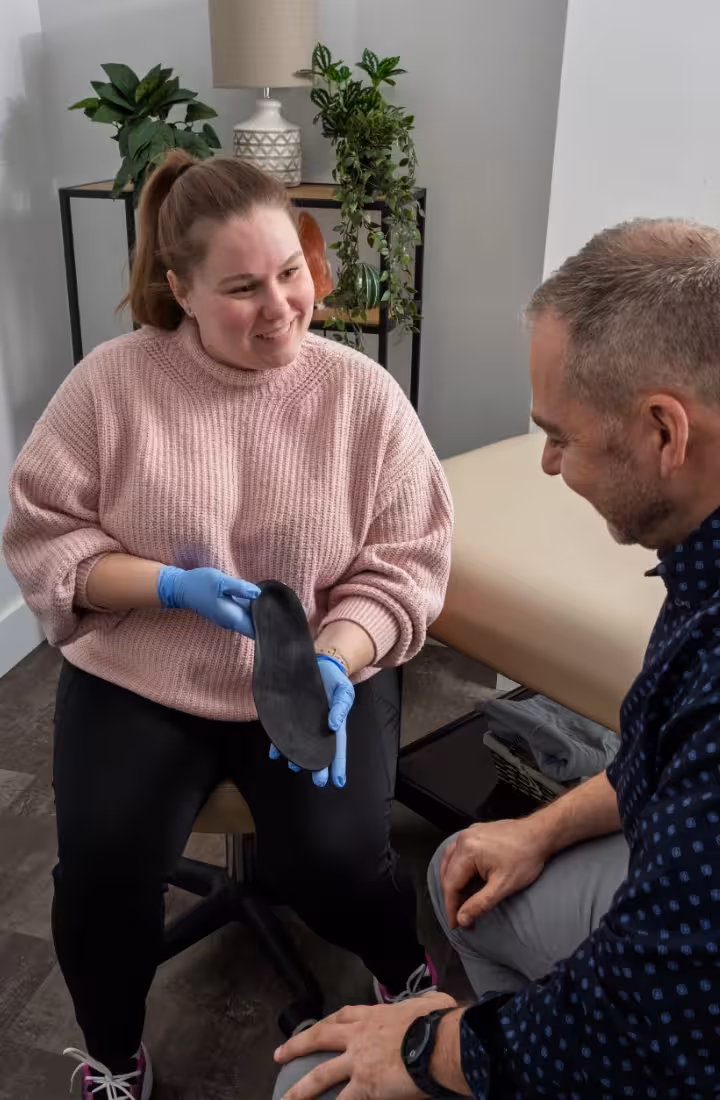 female pedorthist shows finished orthotic to male patient