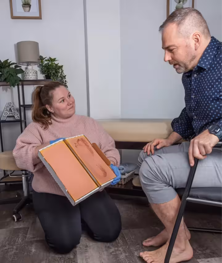 female pedorthist shows orthotics mould to male patient