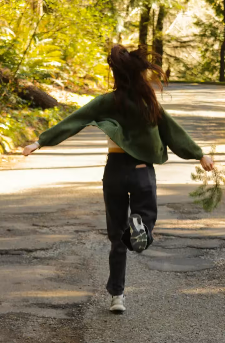Happy woman running through a park now that her feet don't hurt