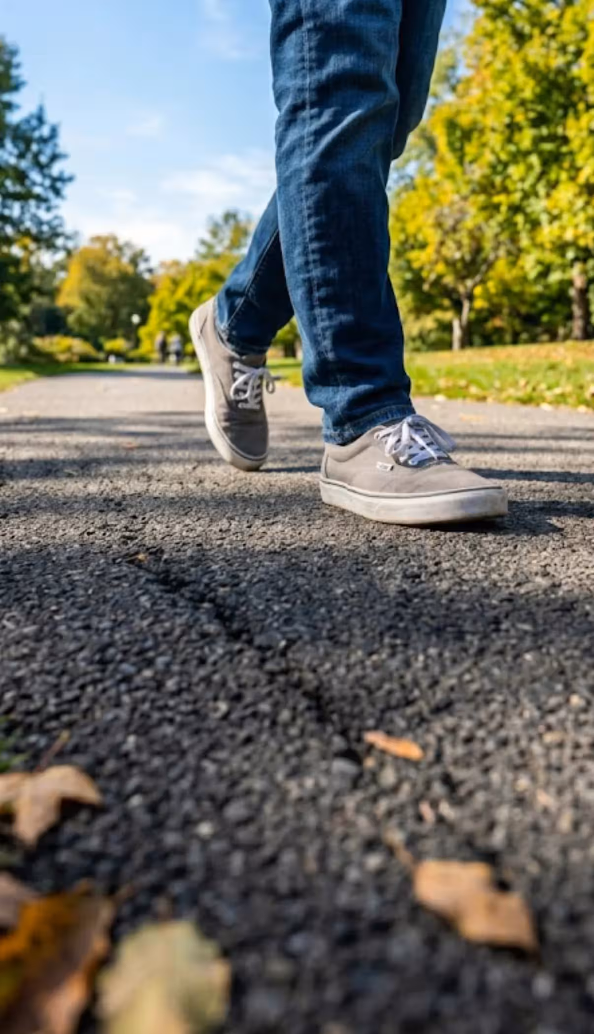 lower legs and feet of a person walking on a paved road
