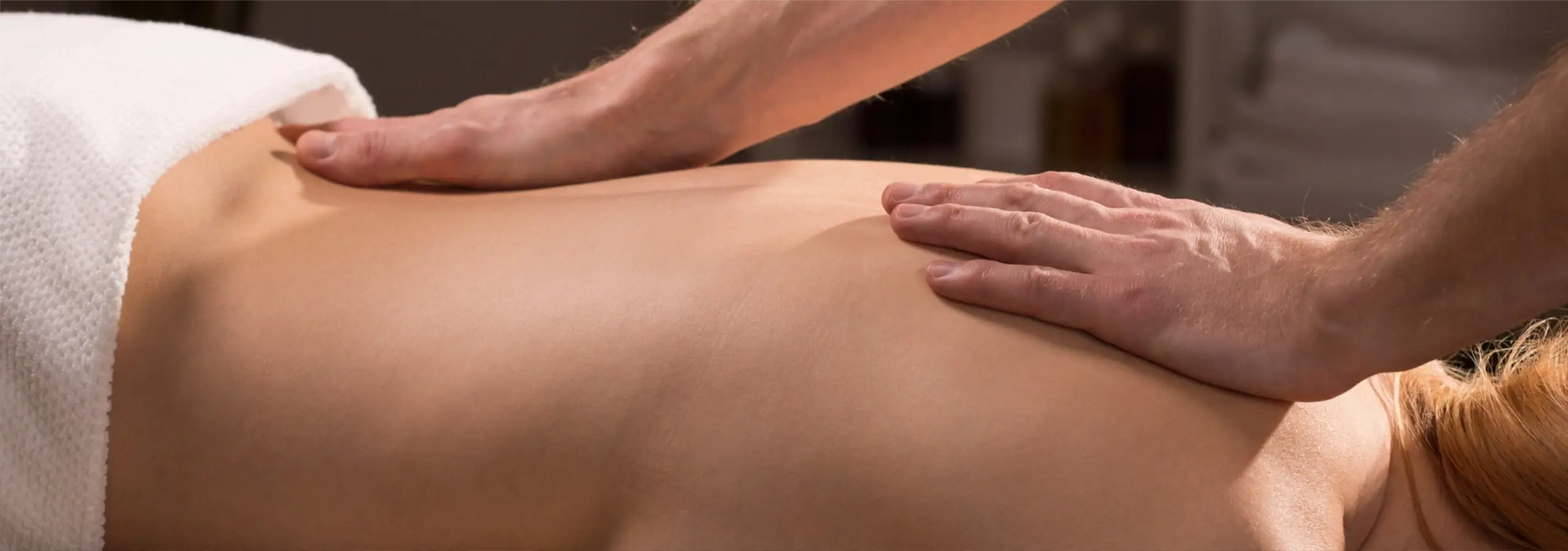 closeup of a registered massage therapist's hands massaging a person's bare back