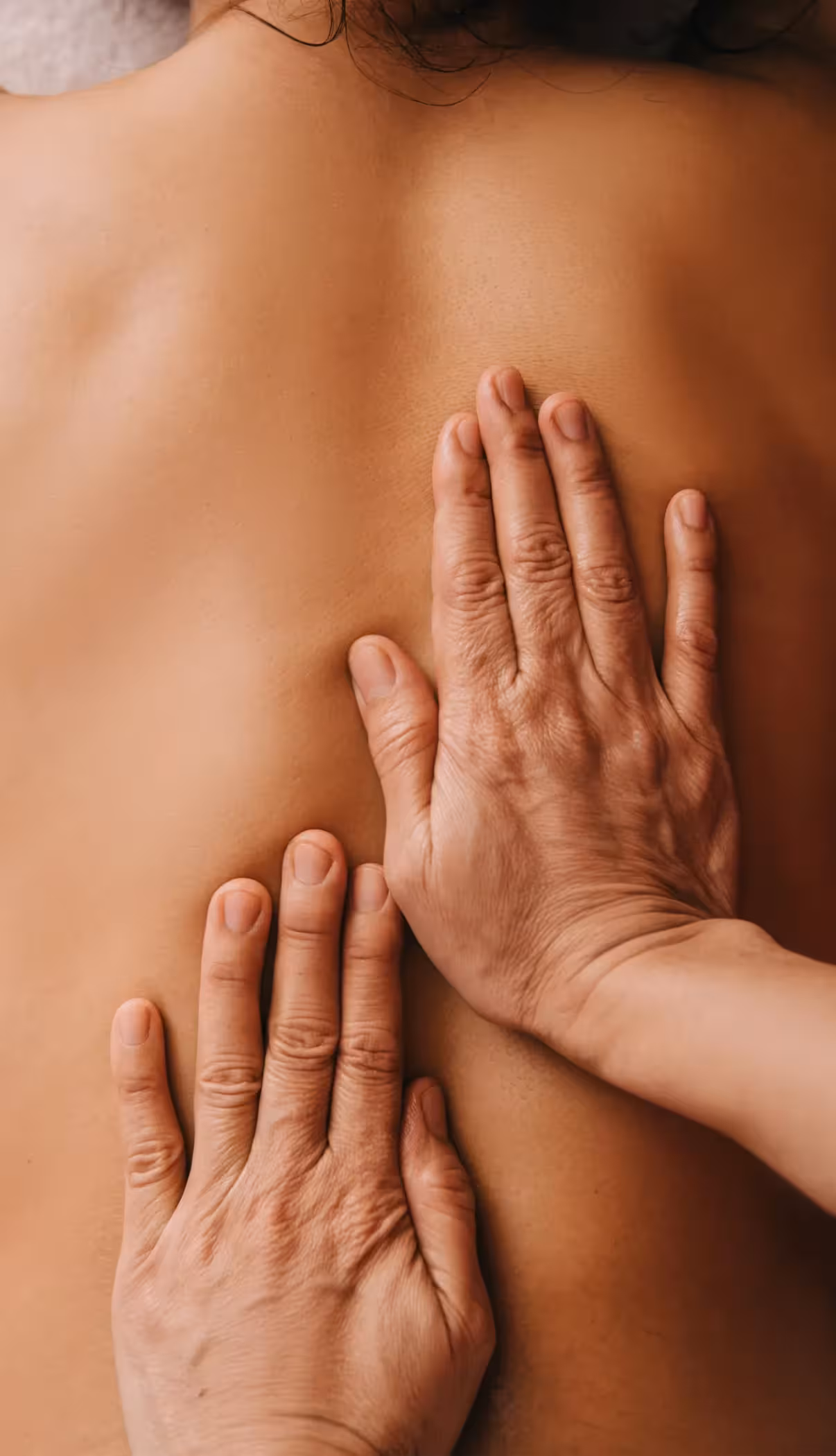 closeup of a registered massage therapist's hands massaging a person's bare back