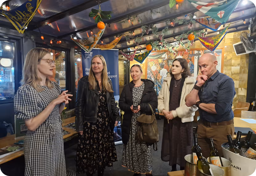Five people gather in a festively decorated room with hanging oranges