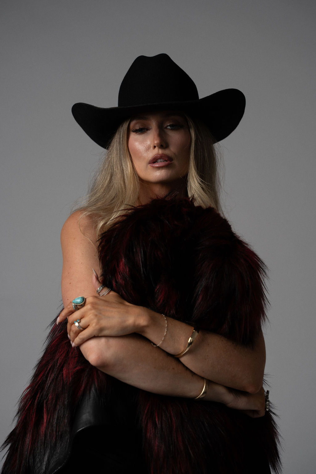 Ashleigh Greenwood in a burgundy feather jacket and black cowboy hat