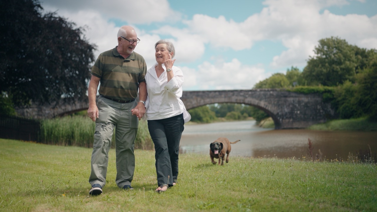Roddy and Elaine walking their dog beside the water