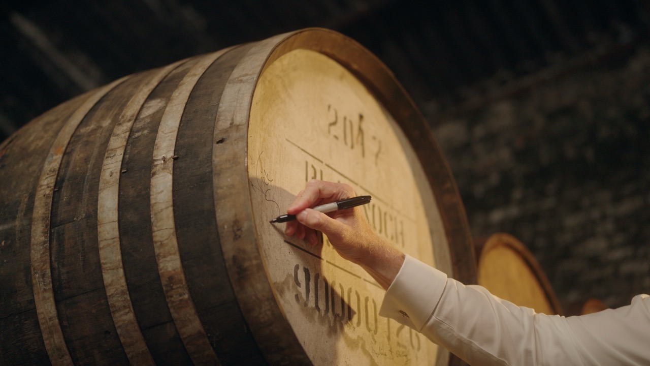 A hand signing the head of a cask at Bladnoch Distillery