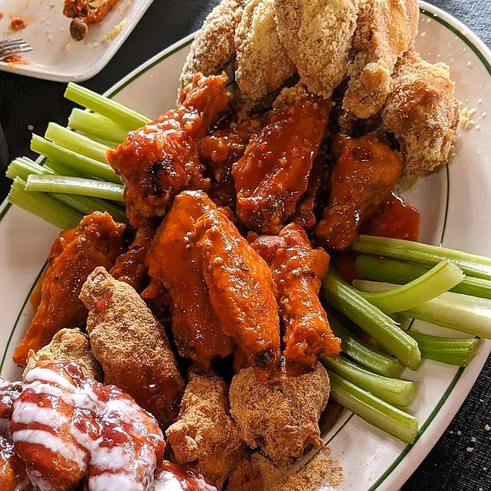 A plate of chicken wings and celery.