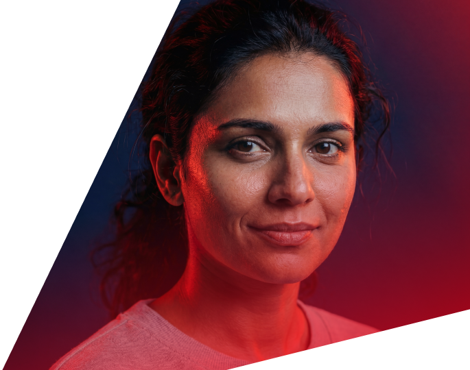 A confident woman with dark hair, illuminated by red and blue lighting, representing innovation and diversity at Faros AI.