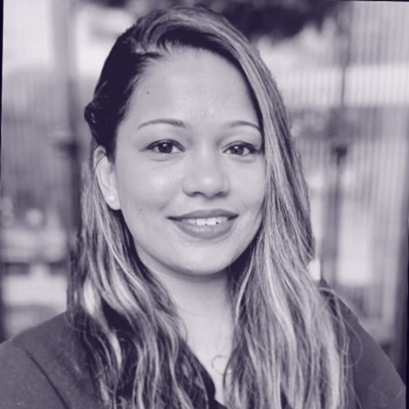 Female professional with long hair smiles confidently, showcasing her role at Faros AI, in a modern outdoor setting.