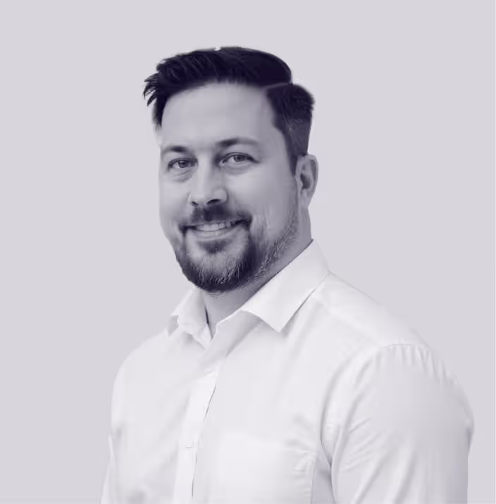 Professional man in a white shirt smiling, representing team members on the Faros AI website.