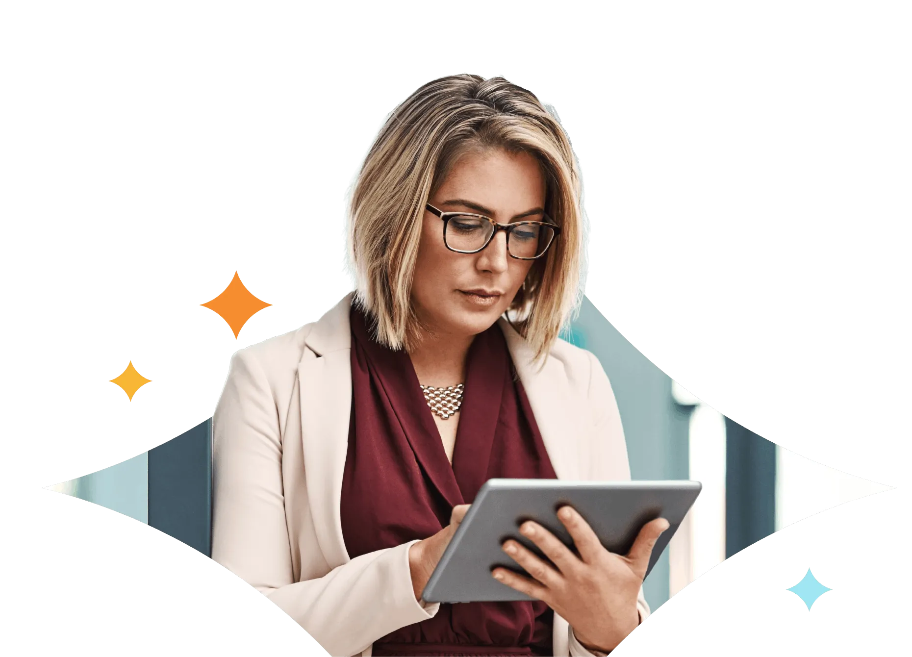 Woman with blonde hair and glasses wearing a beige blazer and maroon blouse, holding and using a tablet.