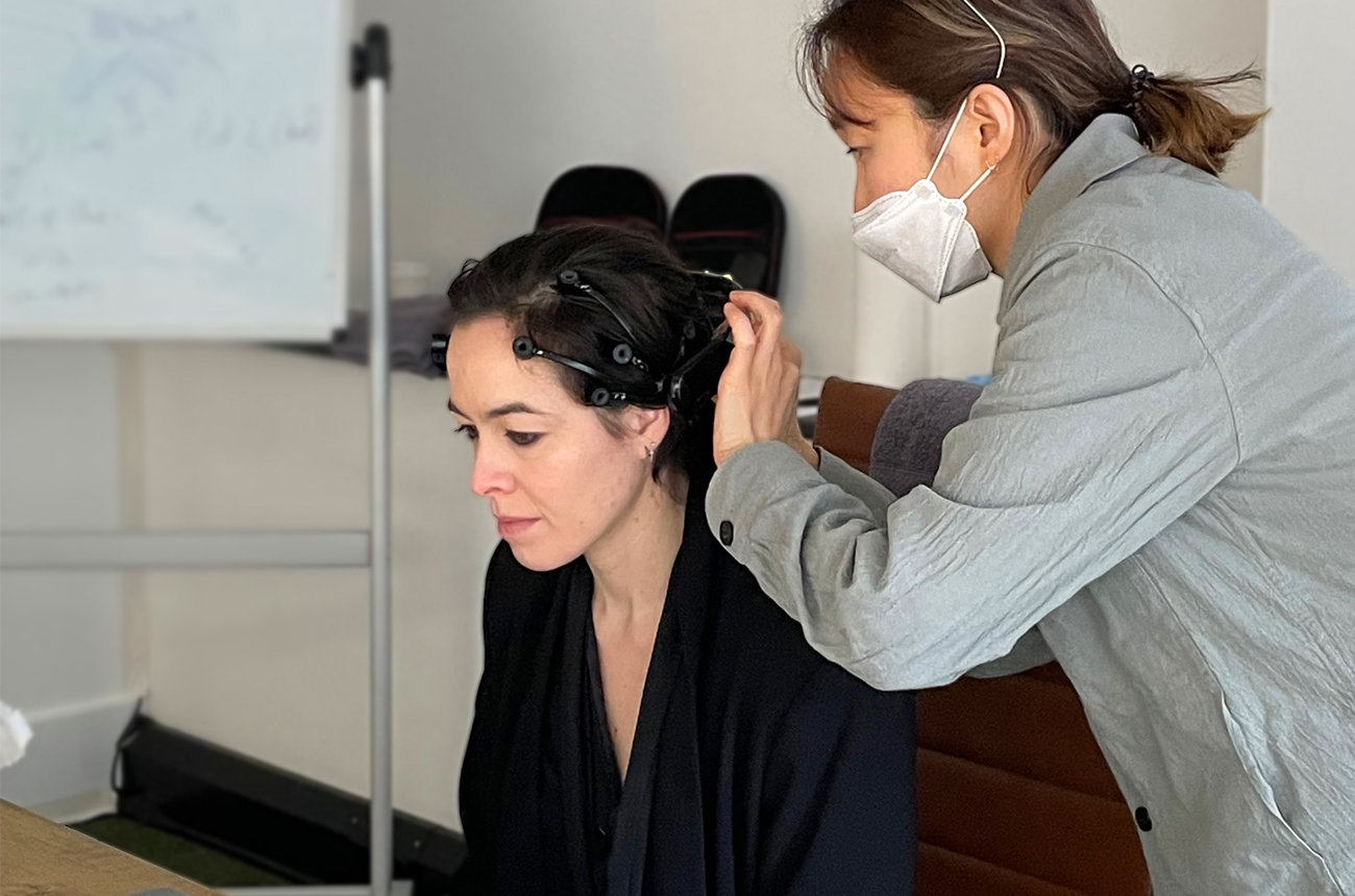A researcher fits an EEG headset to someone in an office