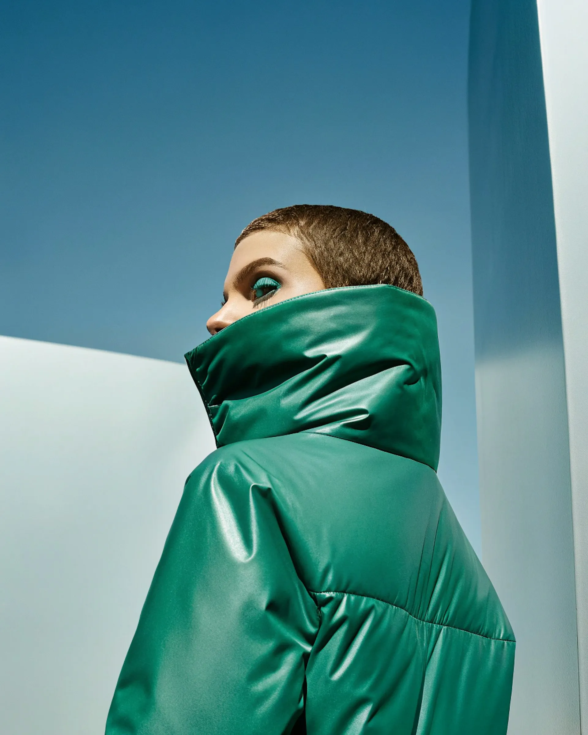 A young man in a green jacket looking off into the distance.