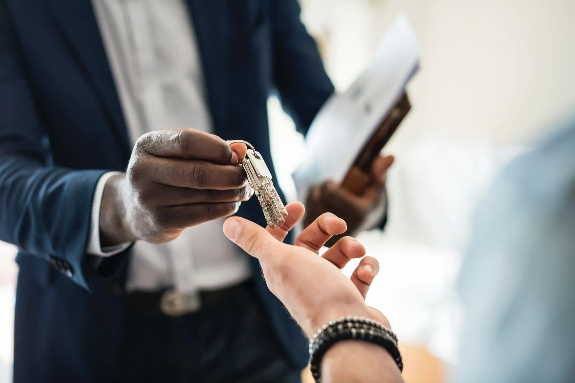 Professional real estate advisor in a suit handing over house keys to an international investor in Tenerife after a successful property closing.