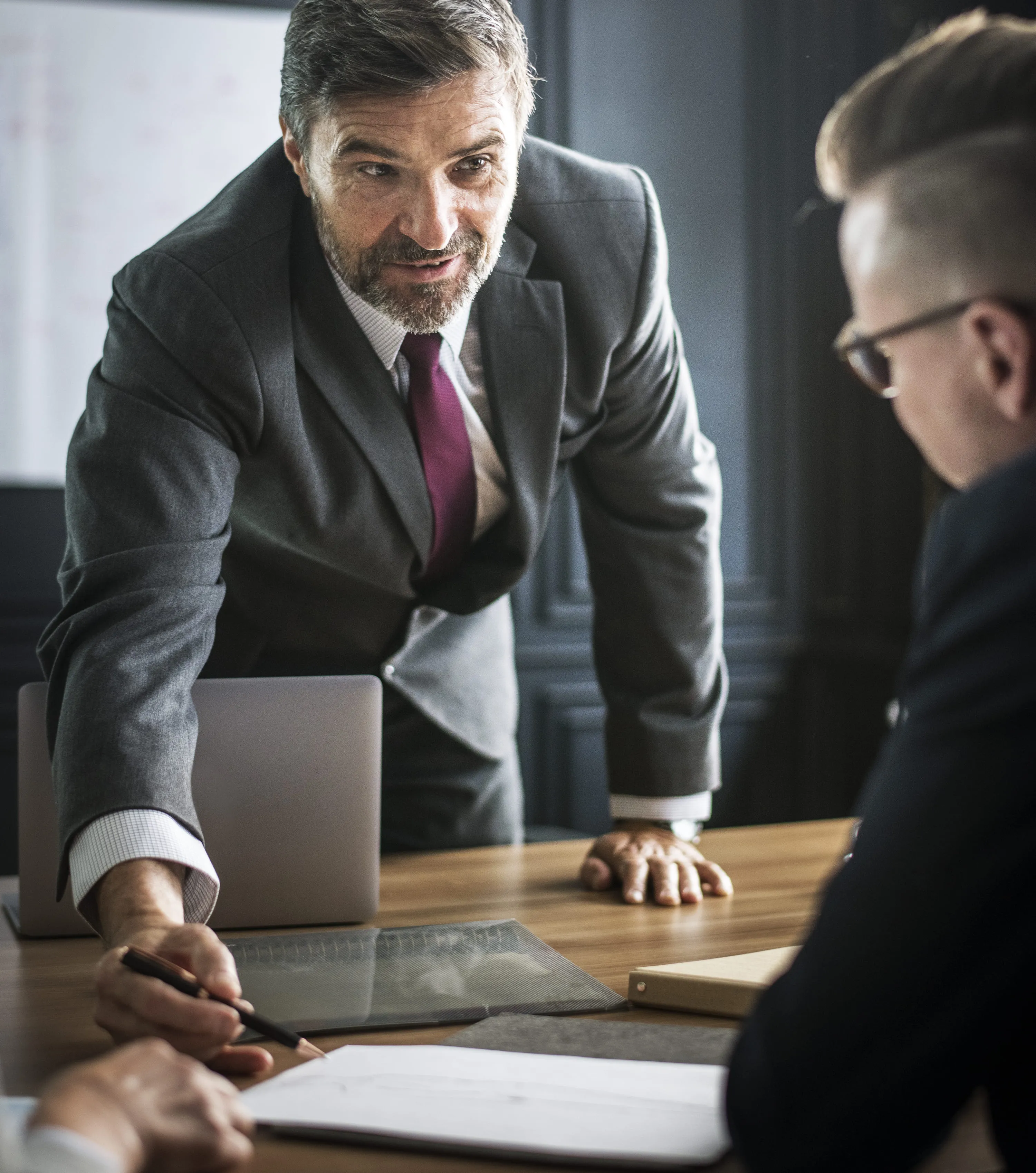 Professional real estate advisor in a suit explaining property investment documents to international clients during a meeting in Tenerife, ensuring legal clarity and transparent service.