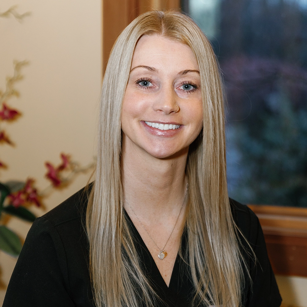 Kristen John, white female with blonde hair, wearing scrubs in The Eye Center office smiling