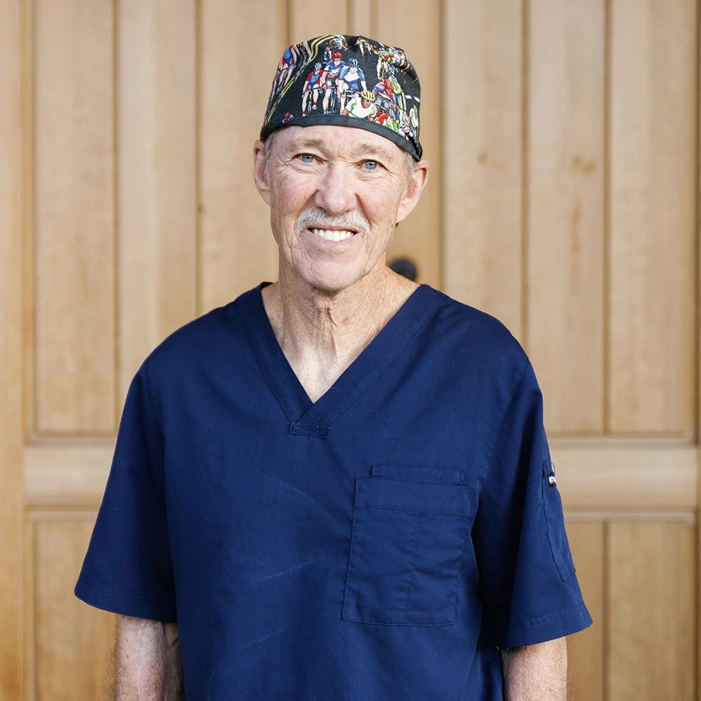 Dr. Ehlers, older Caucasian male, with grey hair and a mustache, wearing a bicyclist surgical cap