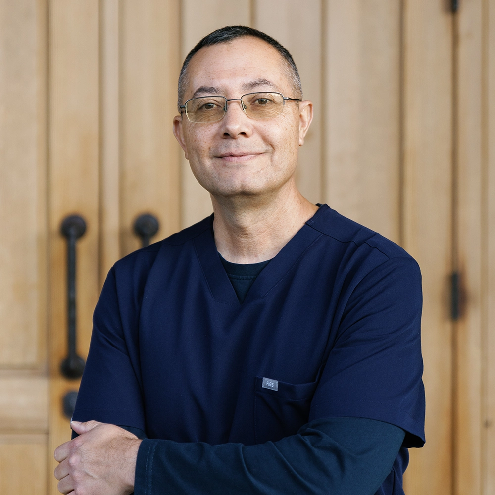 Dr. Jaramillo, Hispanic middle aged man with slat and pepper brown hair, wearing glasses and blue scrubs