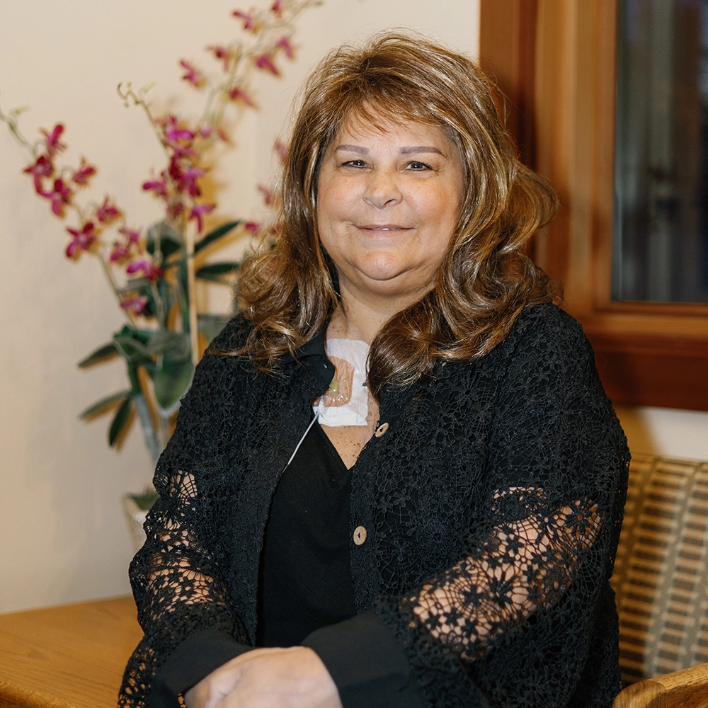 Kristine Thomas, middle aged female with brown curly hair and a warm smile