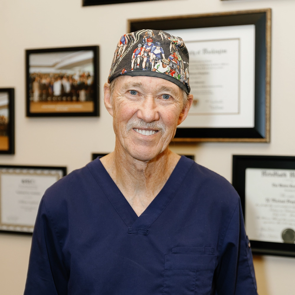 Dr. Ehlers, older Caucasian male, with grey hair and a mustache, wearing a bicyclist surgical cap
