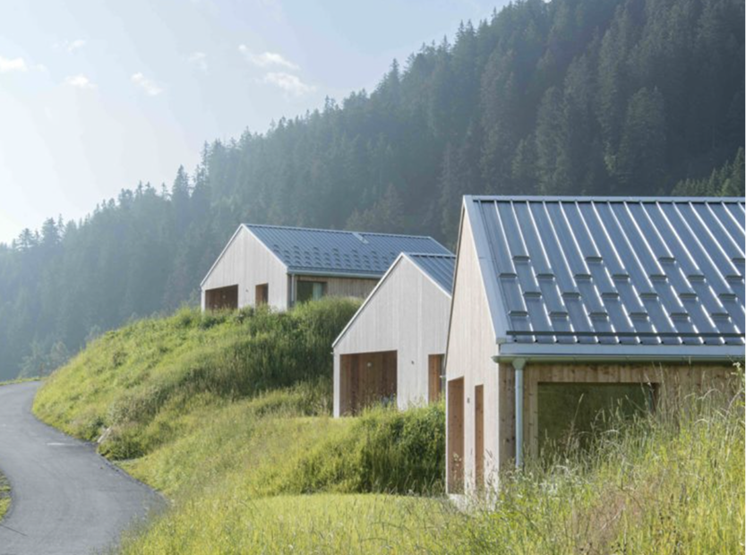 Trois chalets en bois aux toits métalliques le long d'un chemin herbeux – Whitepod, hôtel écologique dans le Valais