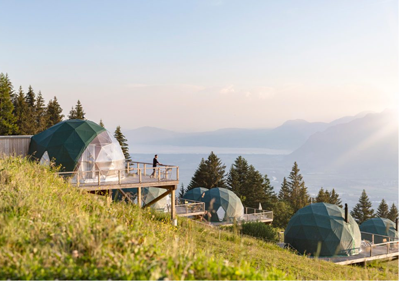 Personne sur la terrasse d'un pod vert face à la vallée brumeuse – Whitepod, hôtel insolite dans les Alpes suisses