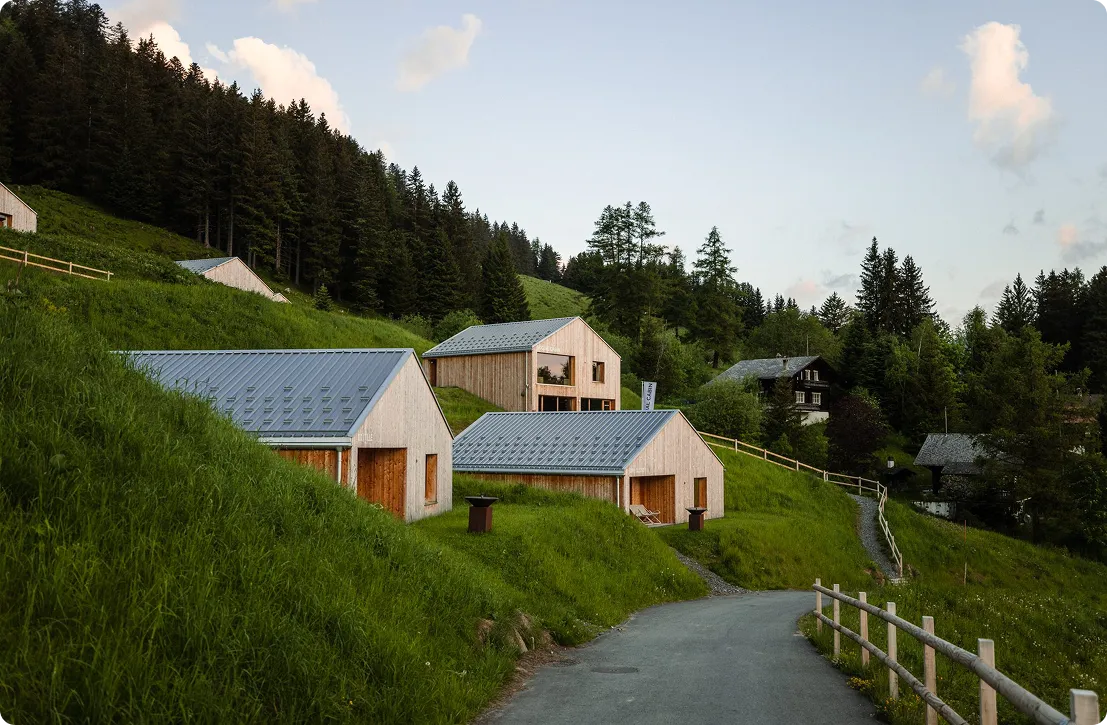 Chalets en bois sur une pente herbeuse au bord d'un chemin – Whitepod, hôtel bulle dans les Alpes suisses